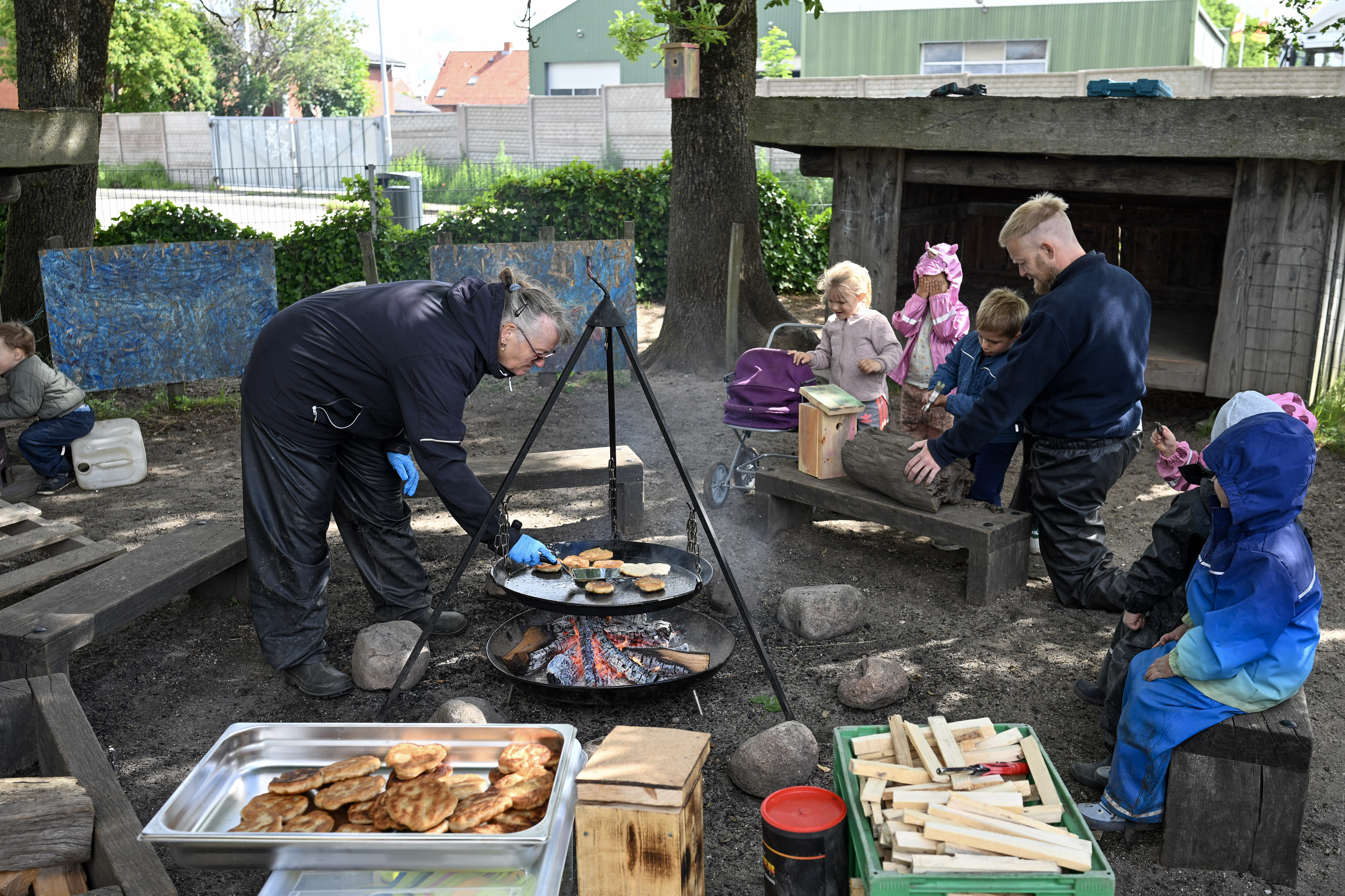 Voksne og børn laver mad over bål